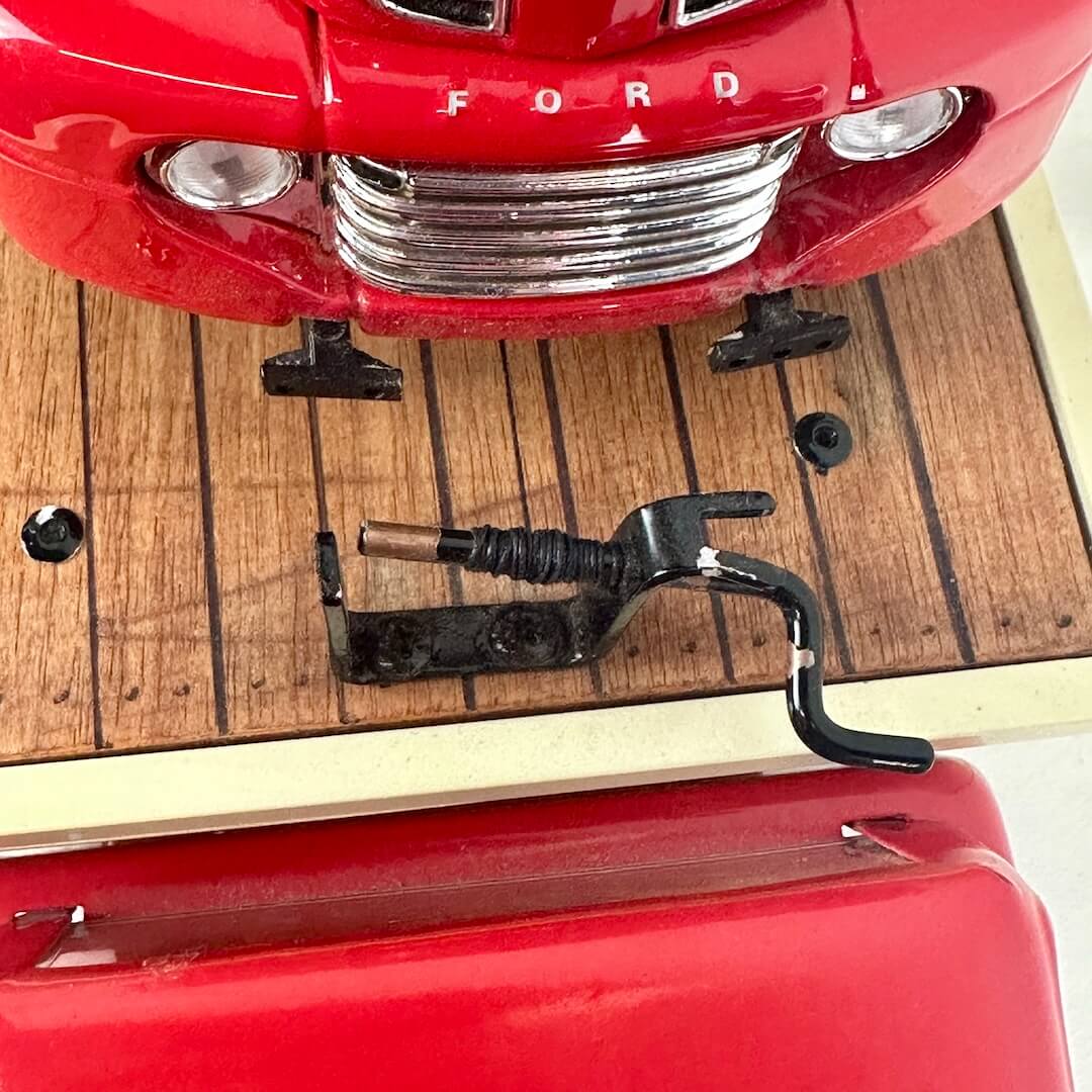 Close-up of a red Ford vehicle's grille and front bumper on a wooden surface.