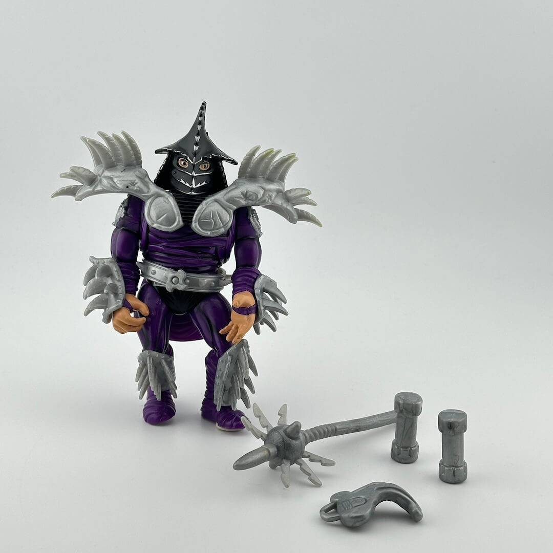 White male figure in all purple with silver spiked samurai armor & black helmet, pictured with silver accessories.