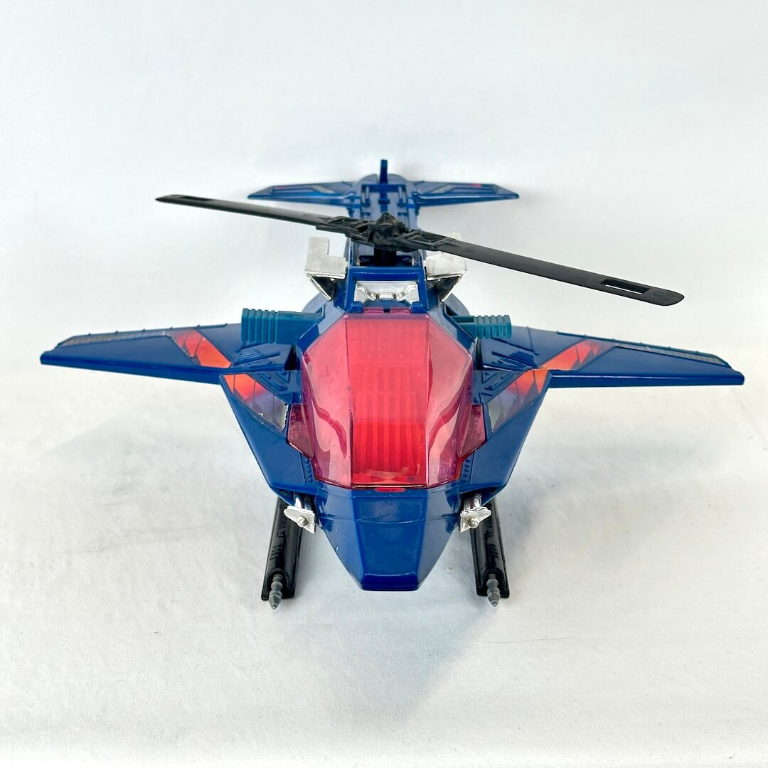 A blue toy jet fighter helicopter with a translucent red canopy and black rotor blades.