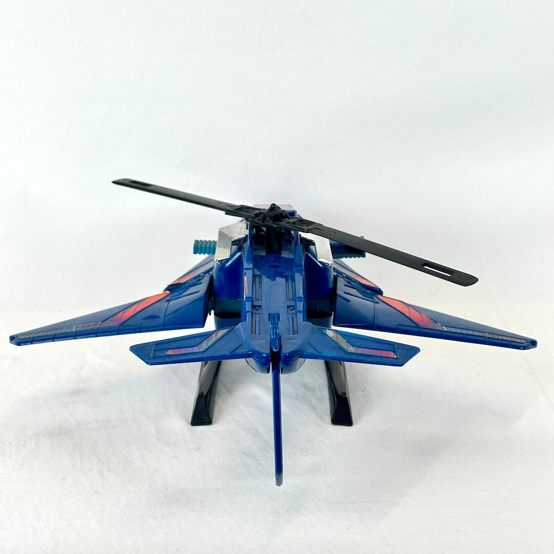 A blue toy jet with black rotors and small red accents, photographed from behind on a plain white background.