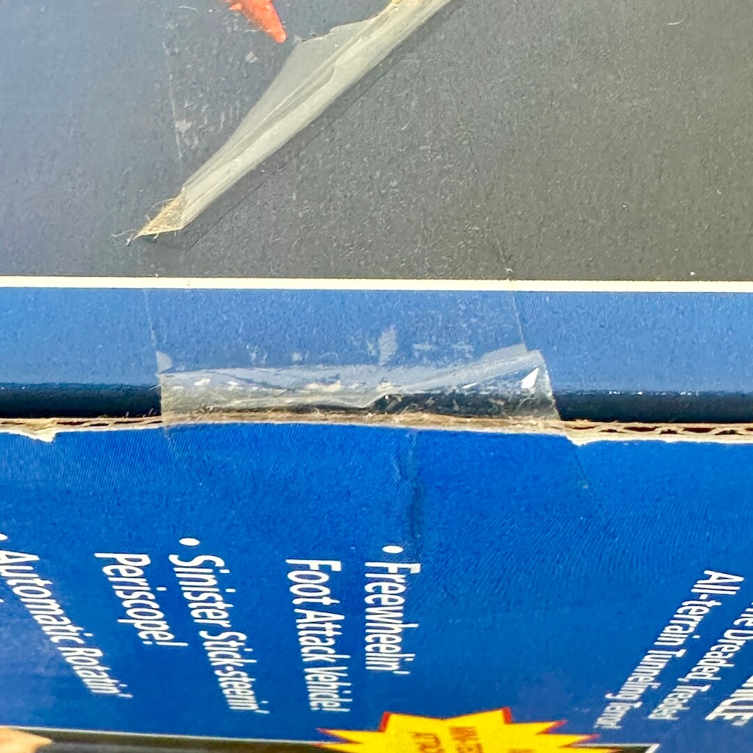 Close-up of a blue toy box with a clear plastic bag containing small items on top.