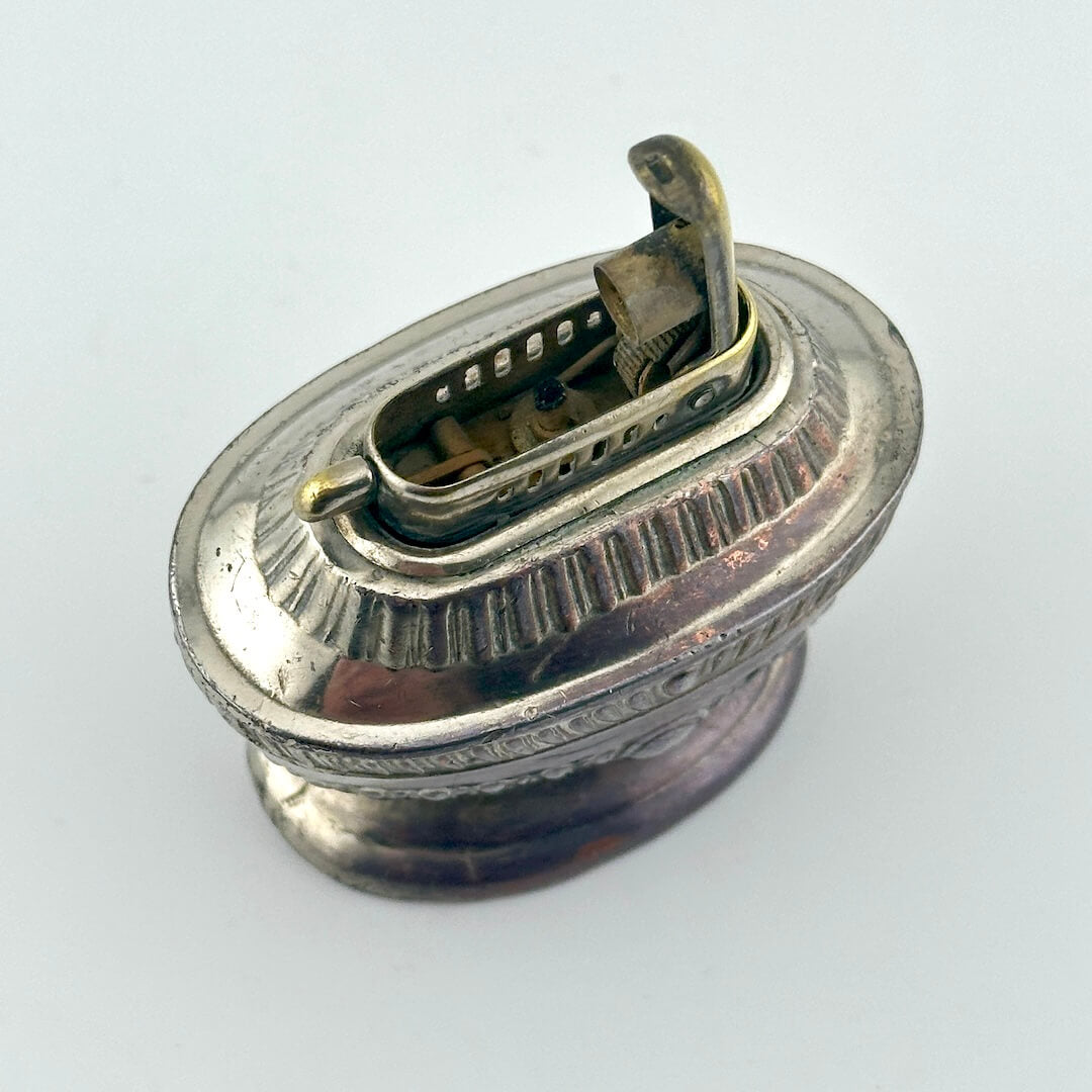 View from top down with lid lifted to show used wick and inner mechanics. 