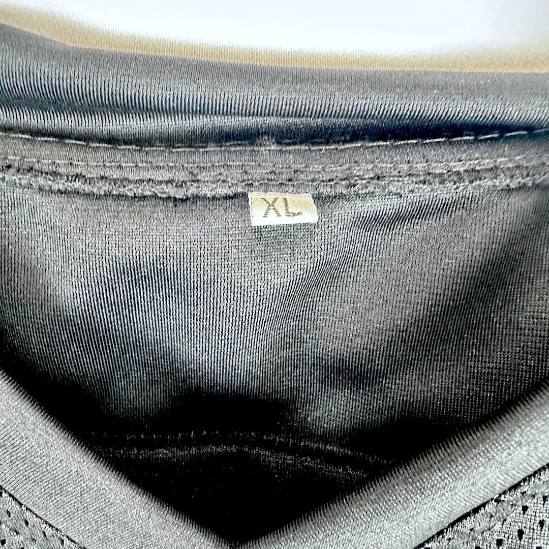 Close-up of the inside neckline of a black knit garment, showing a small size tag marked XL.