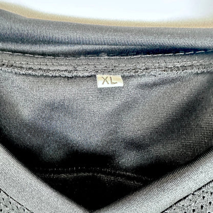 Close-up of the inside neckline of a black knit garment, showing a small size tag marked XL.