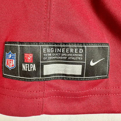 Close-up of a red Nike NFL jersey interior label showing NFL shield, NFLPA logo, and white Nike swoosh on a black patch.