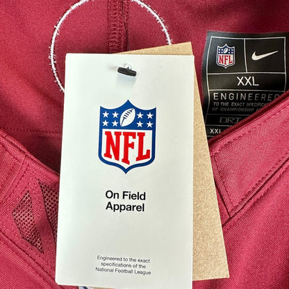 A close-up of a football jersey showing the NFL shield logo on a white hangtag and a black Nike tag indicating XXL size.