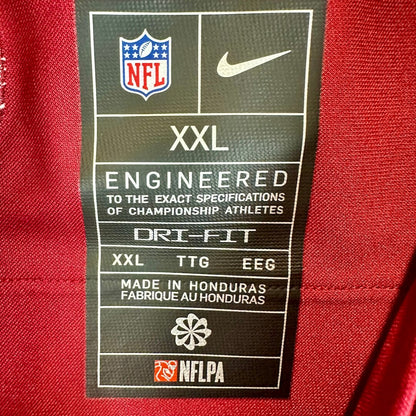 Close-up of a black NFL and Nike garment care label sewn onto a red athletic jersey.