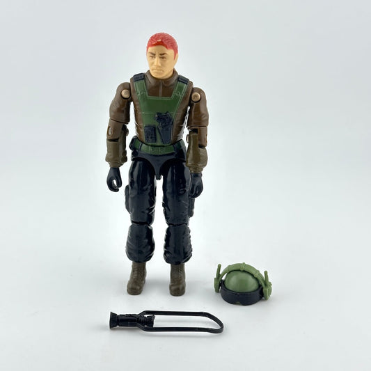 A vintage action figure of a soldier with red hair, wearing a green and brown tactical vest and black pants.