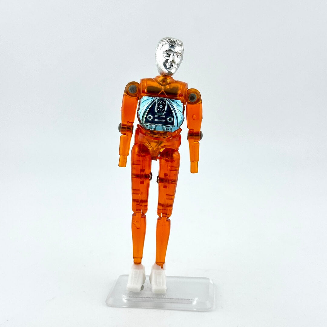 An articulated orange translucent plastic toy figure with a metallic silver head and white hands.