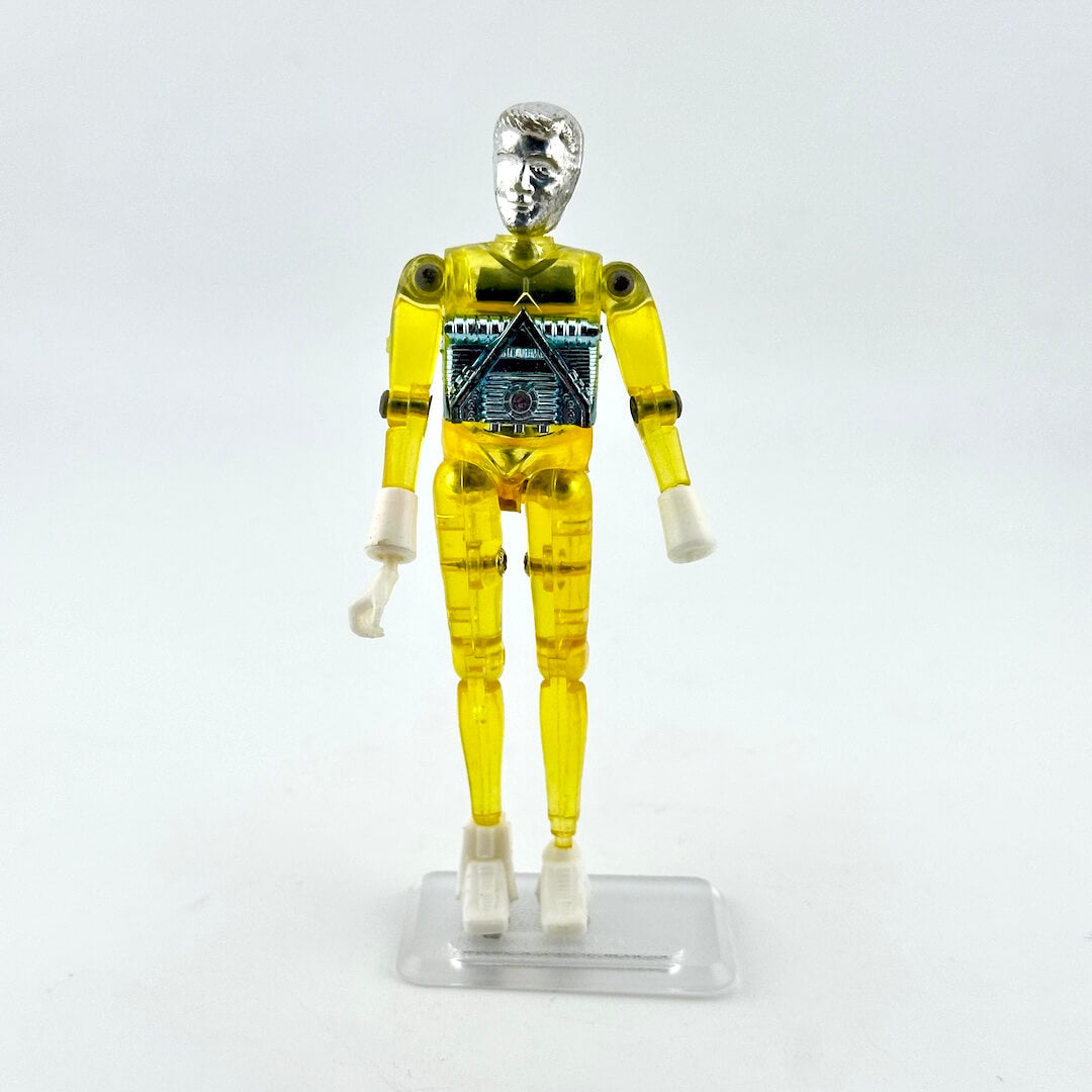 A translucent yellow plastic action figure of a robot or cyborg standing on a clear plastic display base against a white background.