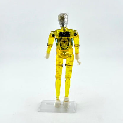 A translucent yellow plastic humanoid action figure or droid standing on a clear plastic display base.