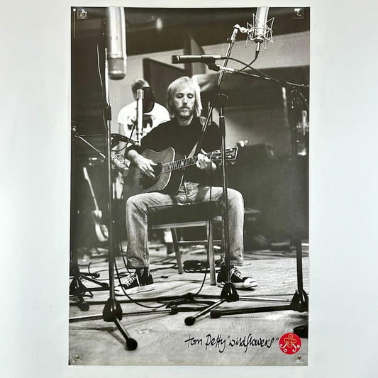 Black and white photo of a musician playing guitar in a studio with 'Tom Petty & The Heartbreakers' logo.