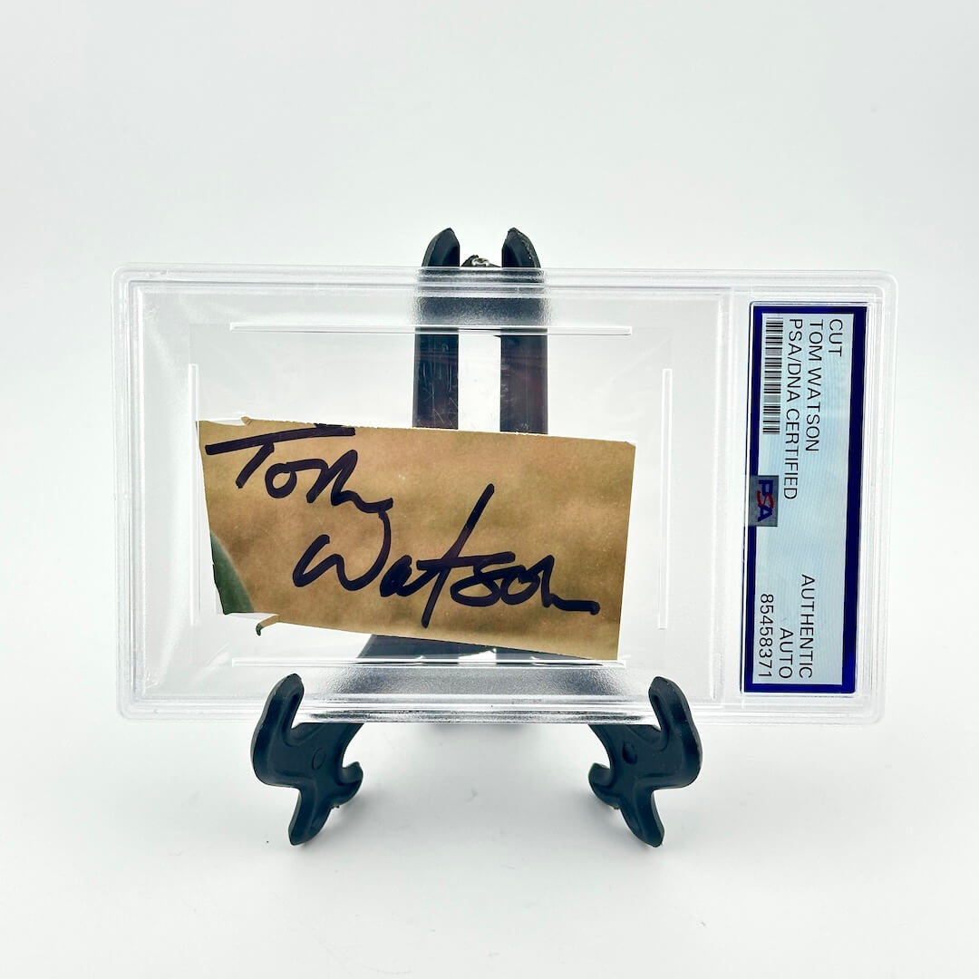 Autographed item on a stand with a clear protective case, featuring a signature and a label.