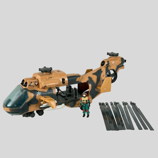A toy helicopter playset in tan and black camouflage, shown with a small soldier figure and dark gray propeller blades.