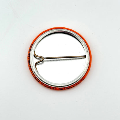 Metallic pin with orange rim on a white background