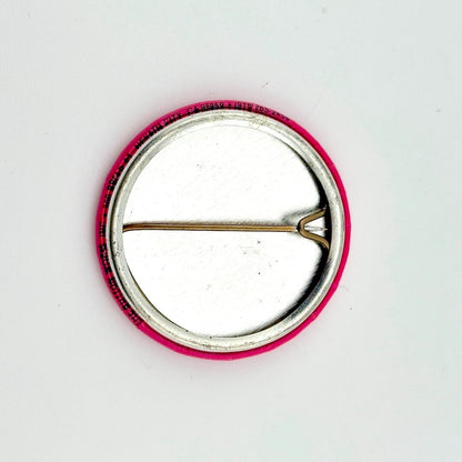 Circular pin with pink border and silver center on a white background