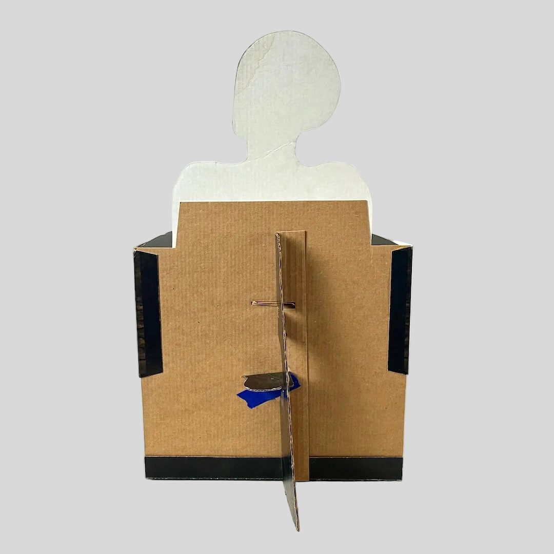 A handmade cardboard display stand or box with a white silhouette cutout on top, photographed against a plain white background.