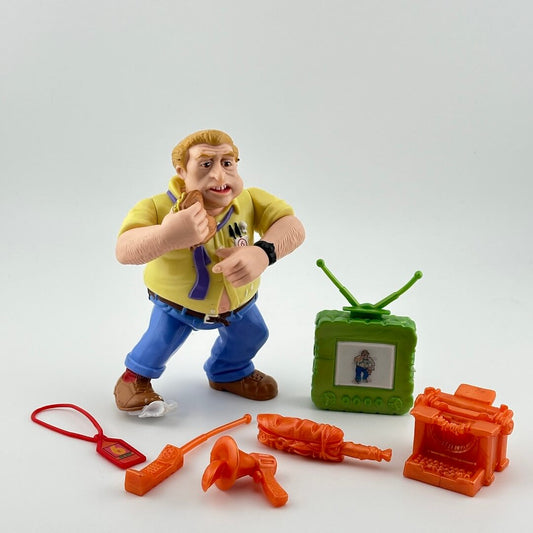 Blonde, overweight, white male in jeans, yellow shirt, purple tie is eating a sandwich; pictured with orange accessories & green TV.