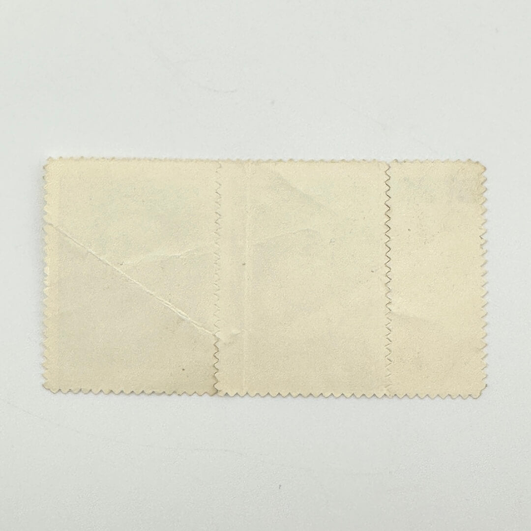 A vintage cream-colored stamp set with scalloped edges, showing signs of age, creases, and wear.