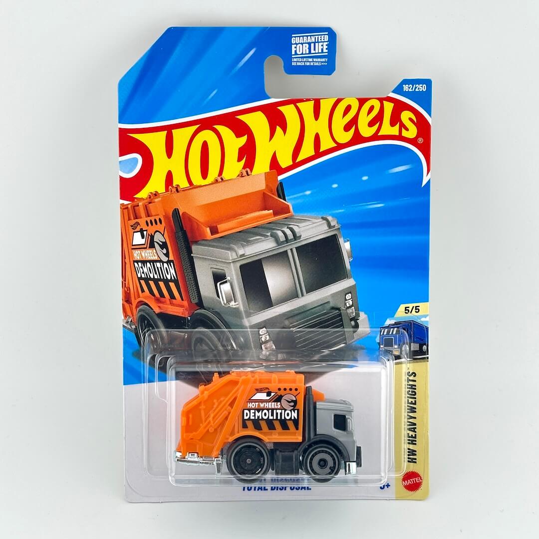 Hot Wheels toy dump truck in orange and gray, packaged on a blue and white blister card with the Hot Wheels logo.