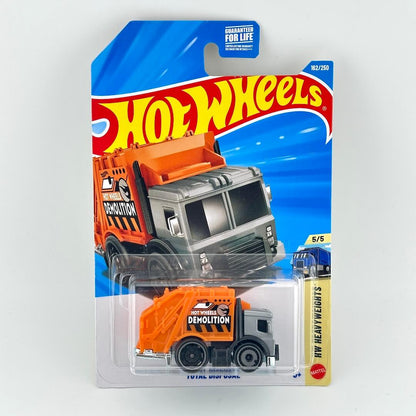 Hot Wheels toy dump truck in orange and gray, packaged on a blue and white blister card with the Hot Wheels logo.