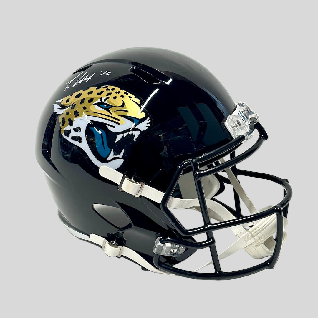 Black helmet with Jacksonville Jaguars stickers/branding against gray background. 