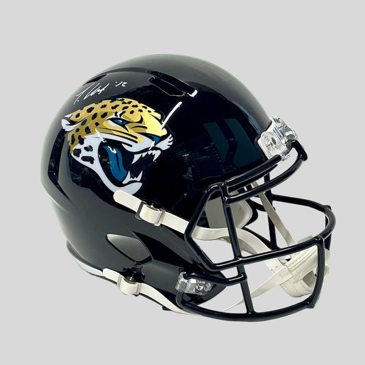 Black helmet with Jacksonville Jaguars stickers/branding against gray background. 