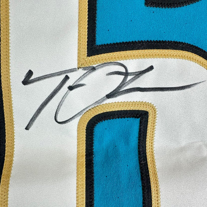Close-up of a sports jersey featuring a large white number with blue and gold border details, signed in black marker.