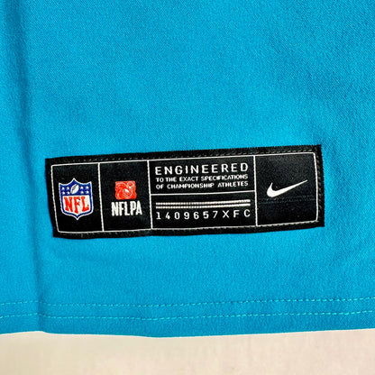 Close-up of a bright turquoise Nike NFL jersey showing the black and white NFLPA tag with NFL and Nike logos.