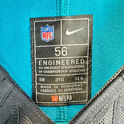 Close-up of an NFL and Nike size tag on a teal football jersey, showing size 56 and manufacturing details.