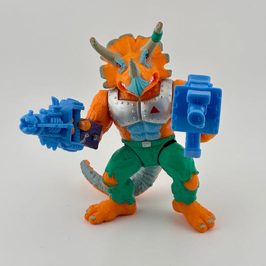 Anthropomorphizes triceratops wearing silver armor chest piece, green pants, holding two large blue guns. Front.