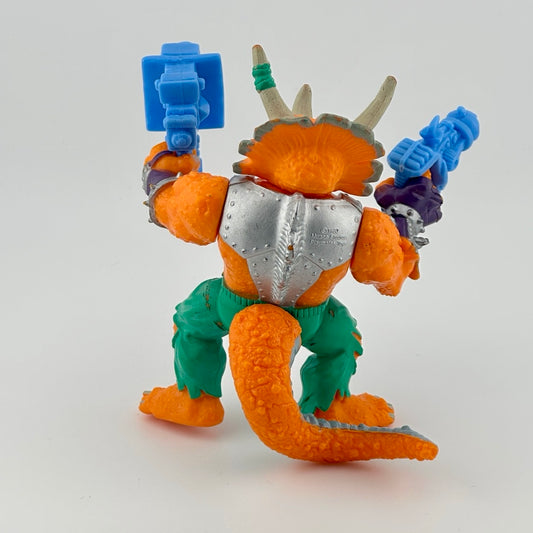 Anthropomorphized triceratops wearing silver armor chest piece, green pants, holding two large blue guns. Back.