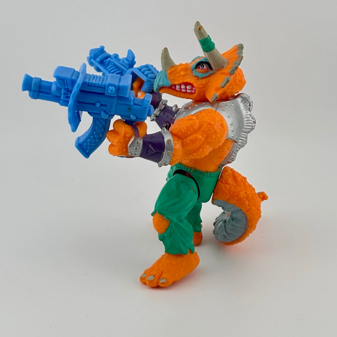 Anthropomorphized triceratops wearing silver armor chest piece, green pants, holding two large, blue guns. Side.