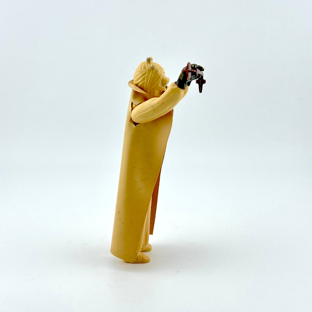 Side view of action figure in beige holding staff on white background. 