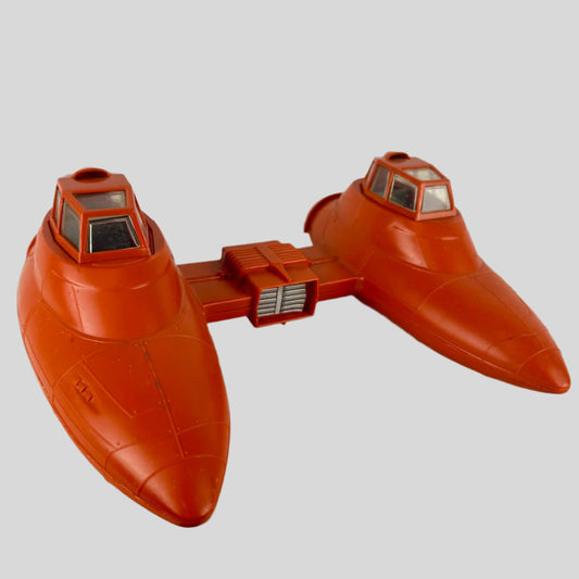 Orange toy spaceship with two compartments attached between them against gray background.