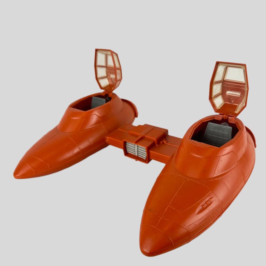 Orange toy spaceship with two compartments attached between them against gray background.