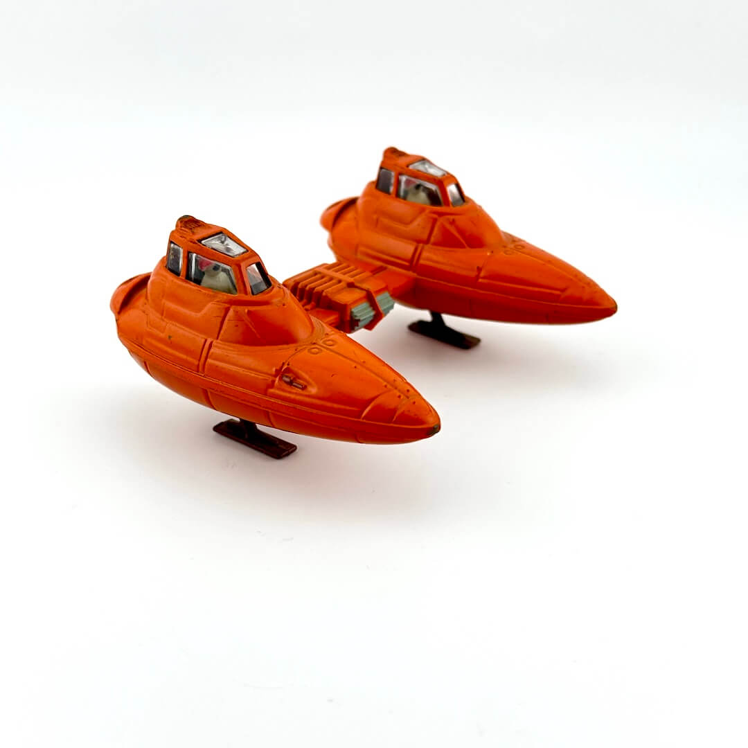 Two-pod orange toy spaceship on a white background
