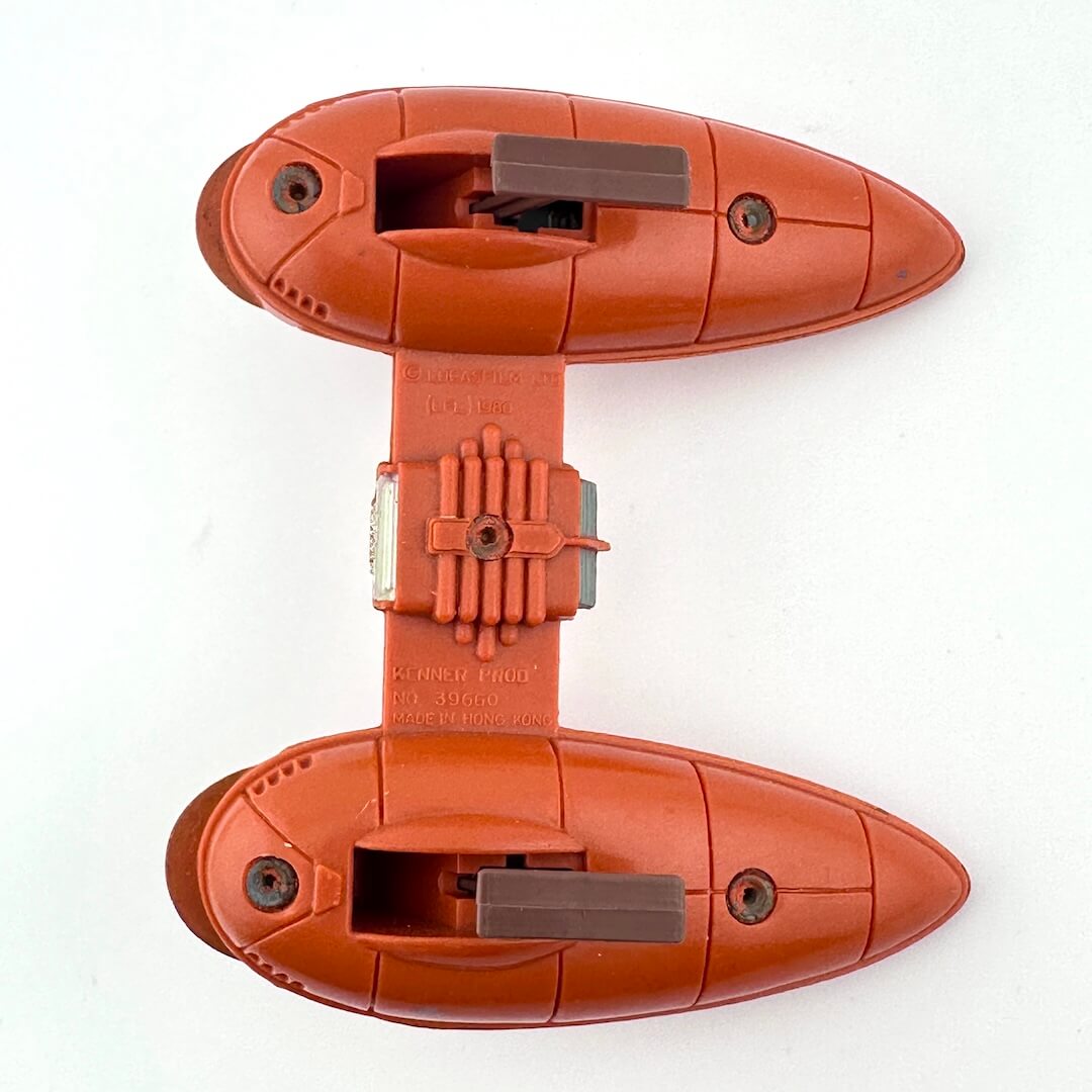 underside of two-pod orange spaceship on white background.