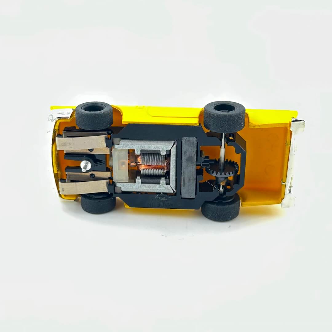 Underside of slot car to show electric components against white background. 