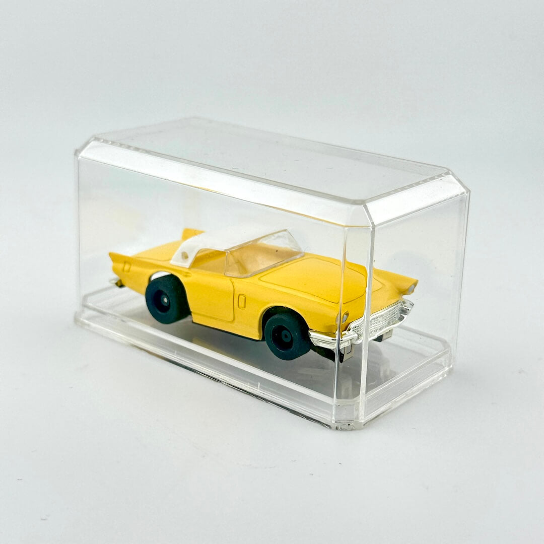 Yellow toy car in a clear display case on a light gray background