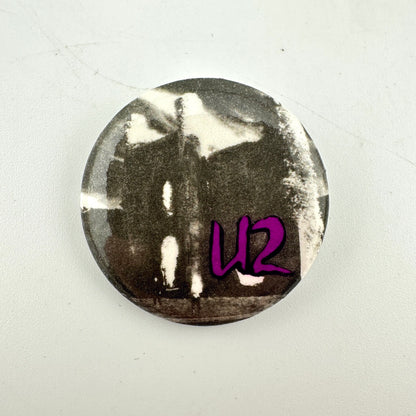 Circular pin badge with black and white image from Unforgettable Fire album and purple, 'U2' 