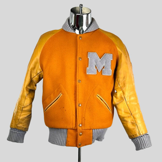 Orange jacket with lighter orange sleeves. Cuffs, collar & waistband all ribbed grey. "M" on breast in grey.