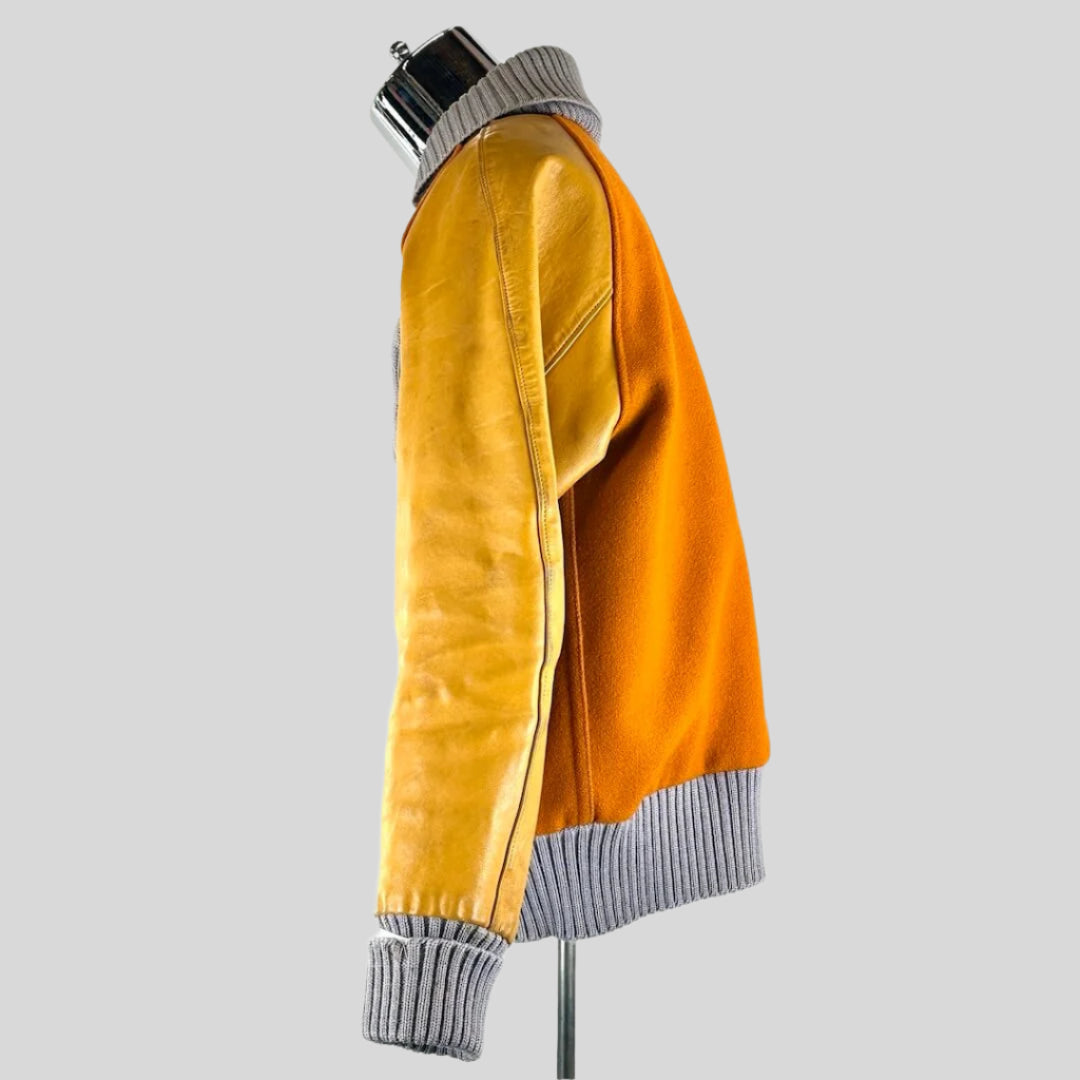 side view of orange varsity jacket with lighter orange leather sleeves, ribbed grey collar, cuffs and waistband.