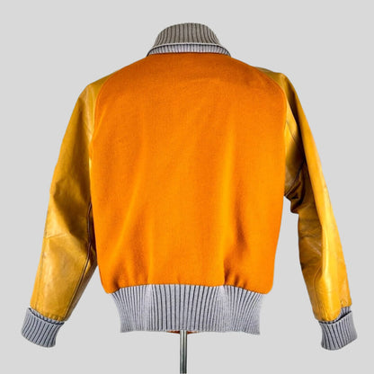 back view of orange varsity jacket with lighter orange leather sleeves, ribbed grey collar, cuffs and waistband. 