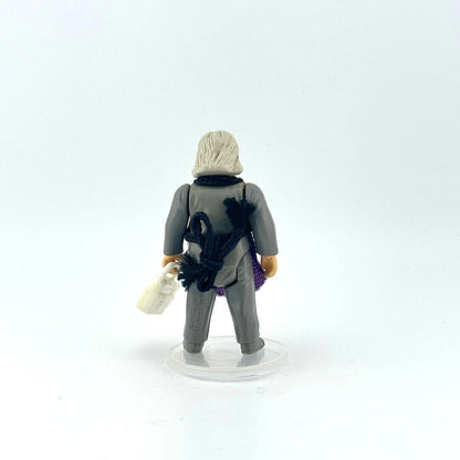Alien action figure in gray outfit and purple apron holding white briefcase against white background.