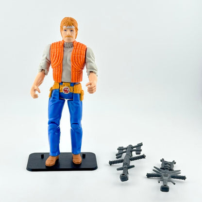 Action figure rin blue pants and orange vest with two accessories against white background.