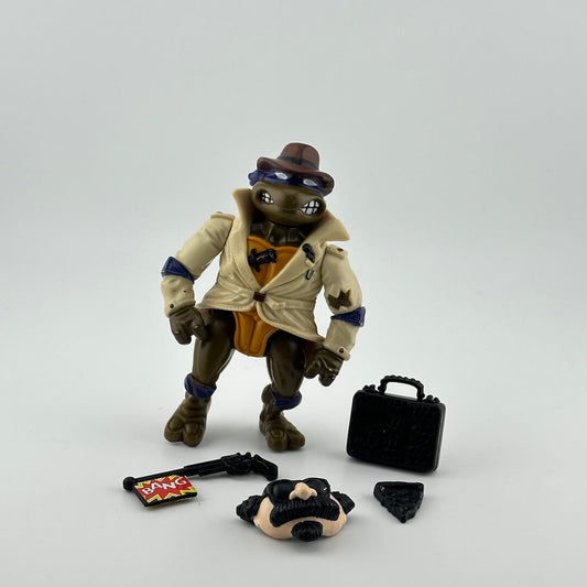 Anthropomorphized turtle in purple mask wearing beige trenchcoat, pictured with disguise mask, briefcase, & black pizza slice.
