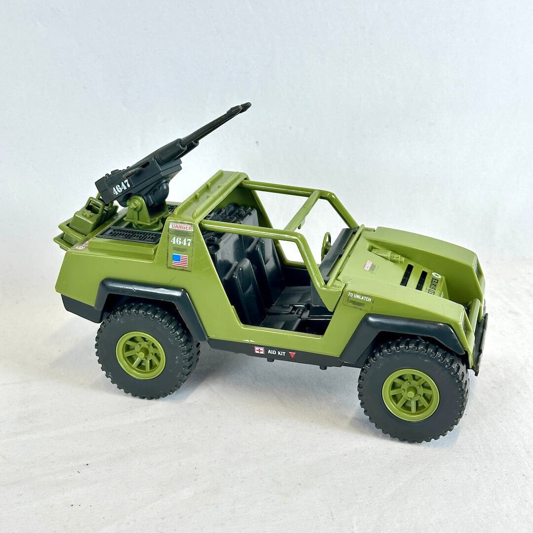 An olive green military-style toy jeep with black tires, black interior seats, and a mounted black gun turret.