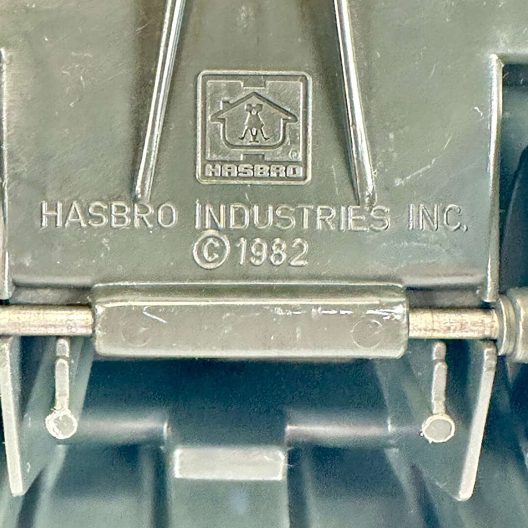 Close-up of embossed HASBRO Industries Inc. branding on a dark gray molded plastic surface.