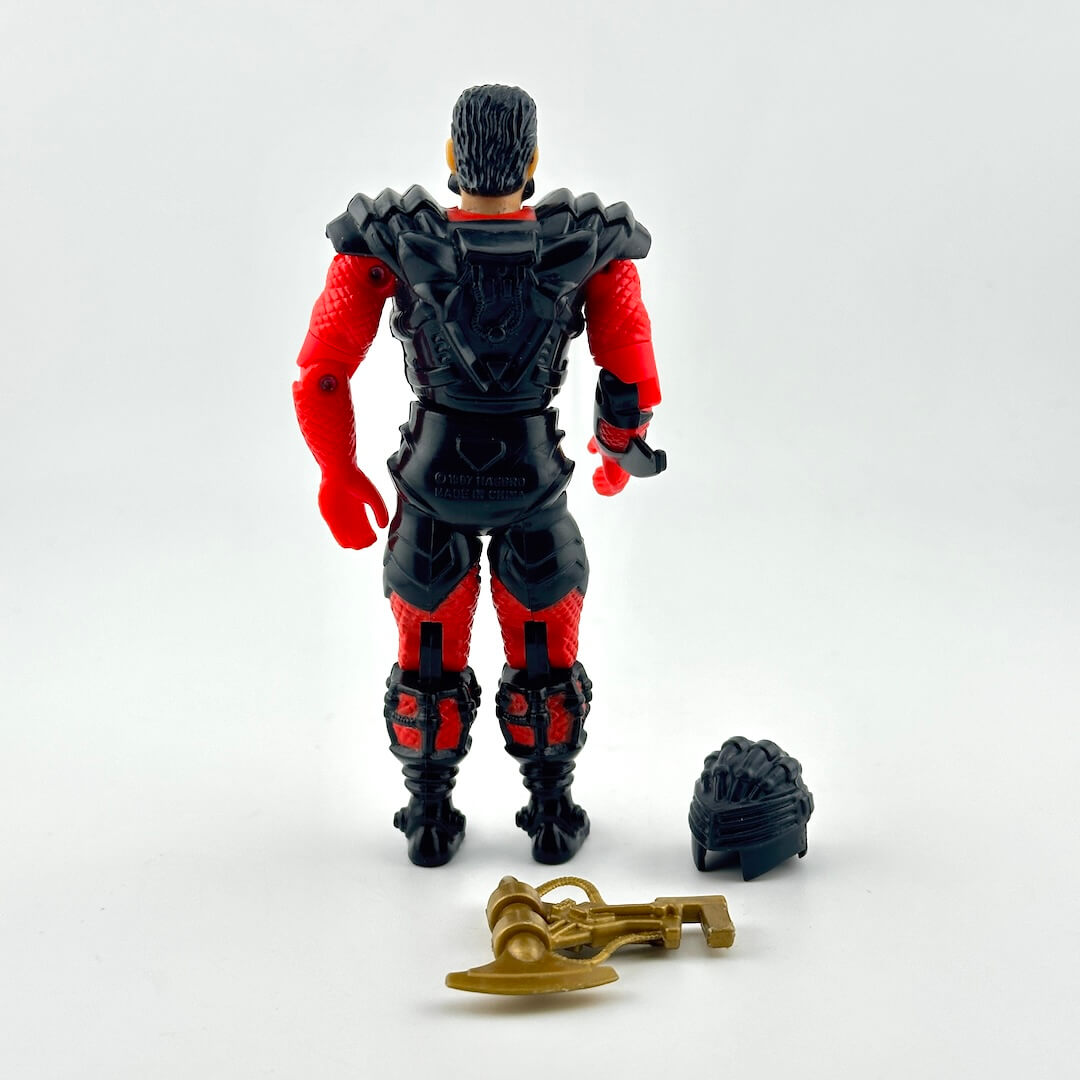 A red and black armored action figure with a green chest panel, shown with two accessories on white background. 